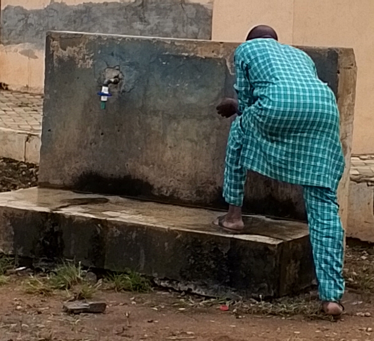 A Man Fetching Water In a Public Tap in Offa