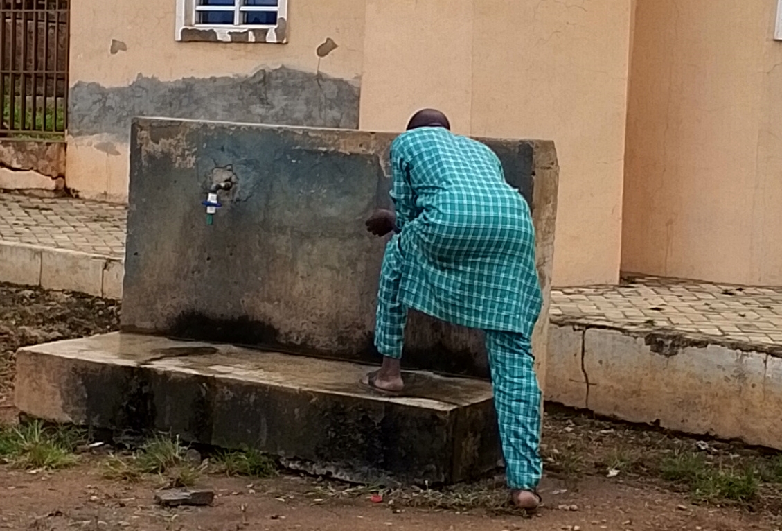A Man Fetching Water In a Public Tap in Offa