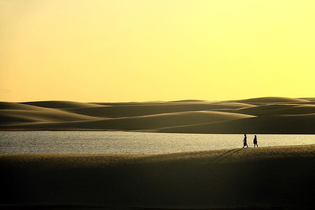 Casal de turistas caminha em uma duna, enquanto o dia morre nos Lençóis Maranhenses (edited)
