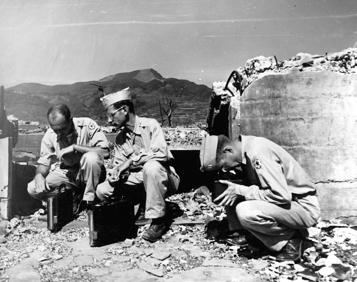 Amid the wreckage of a prison in Nagasaki, three Manhattan Project specialists use Geiger counters to measure residual radioactivity